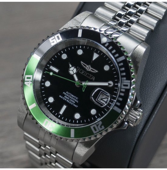 Automatisch herenhorloge met zwarte wijzerplaat, groene lunette en zilverkleurige band.