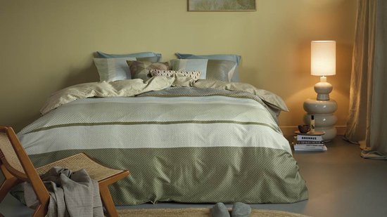 Une chambre avec un lit fait avec une housse de couette verte à rayures.