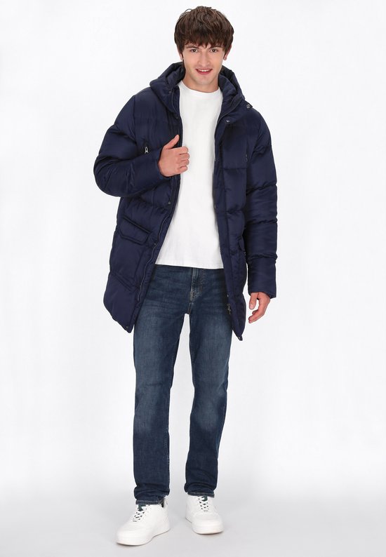 Man in donkerblauwe gewatteerde parka met capuchon, wit T-shirt en spijkerbroek.