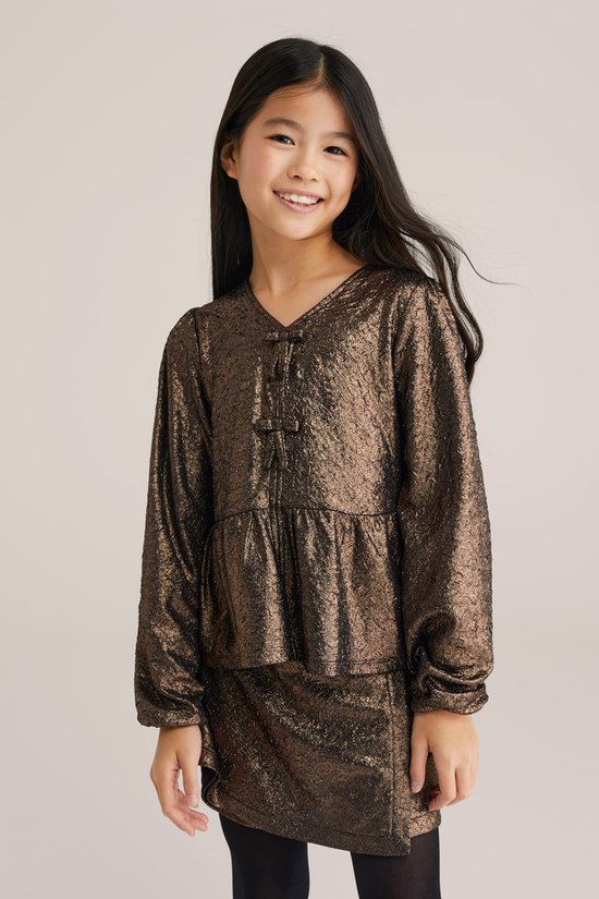 Close-up van meisje in bruin metallic peplum T-shirt met strikdetail.