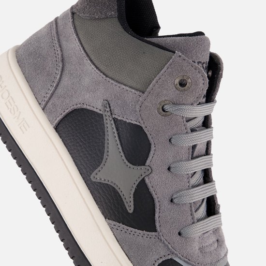 Gedetailleerde kijk op grijze sneakers met zwarte ster en veters.