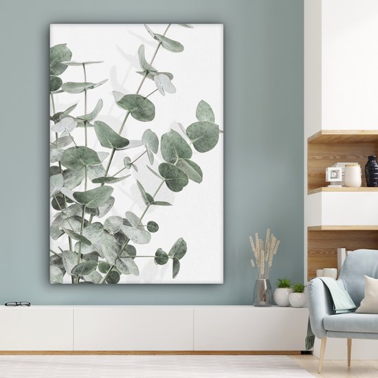 Canvas van eucalyptusbladeren in een moderne woonkamer boven een witte kast.