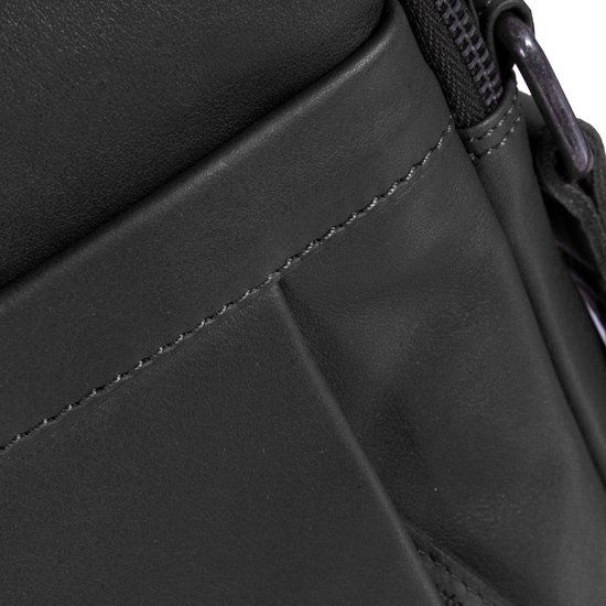 Detail van de stiksels op een zwarte leren tas met een steekvak.