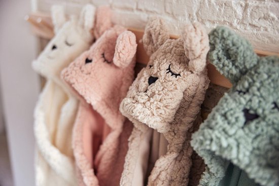 Witte, roze, beige en groene baby wikkeldekens met dierenoren hangen aan haken.
