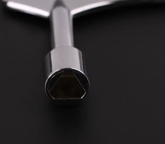Gros plan de la douille carrée d'une clé triangulaire métallique brillante.