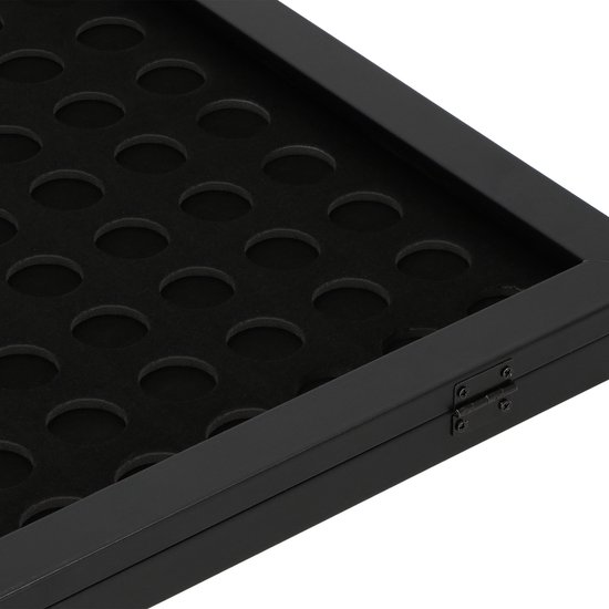 Detail van zwarte lijst, scharnier en cirkelvormige uitsparingen voor capsules.