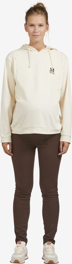 Een zwangere vrouw draagt een off-white hoodie met een klein logo op de borst en een bruine legging.