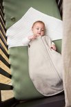Baby ligt in een wieg in een beige slaapzak met streepjesdekentje.