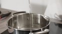 Water wordt in een roestvrijstalen pan gegoten, met maataanduidingen.