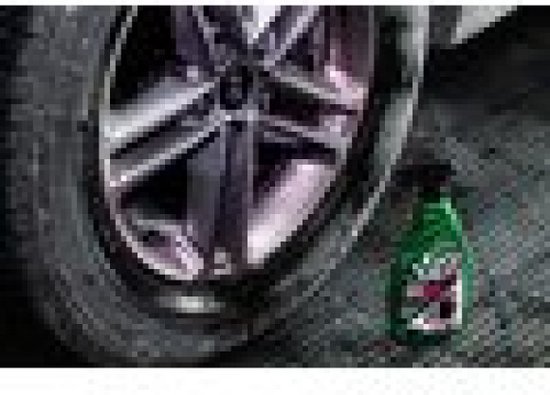 Une bouteille verte de Turtle Wax Redline à côté d'une jante de voiture.