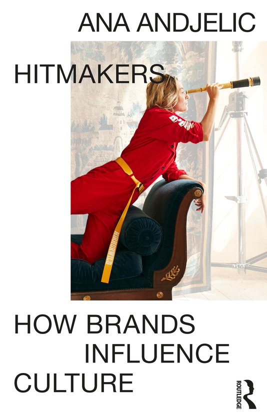 Vrouw in rood jumpsuit kijkt door telescoop, zittend op een donkerblauwe bank. Titel: Hitmakers. Auteur: Ana Andjelic. How Brands Influence Culture.