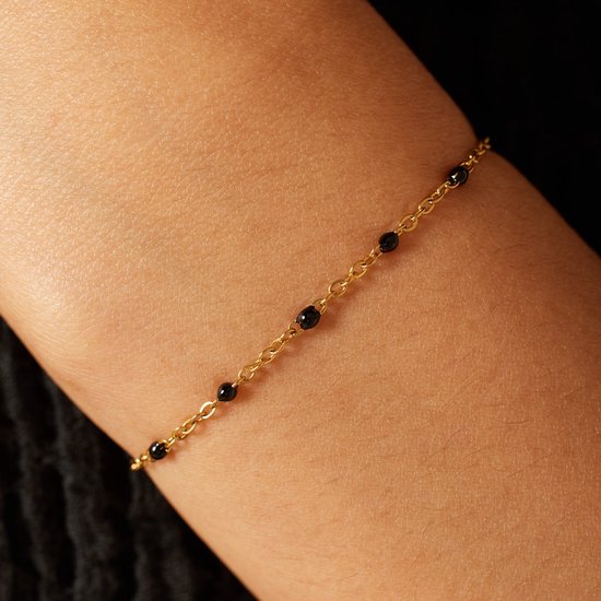 Dichtbij op de arm: gouden armband met kleine zwarte kraaltjes.