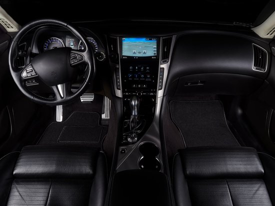 Intérieur de voiture moderne avec tableau de bord noir, volant et sièges en cuir.