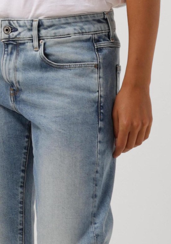 Model in een lichtblauwe G-Star jeans, met witte sneakers en witte T-shirt.