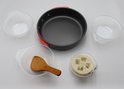 Zwarte camping kookpan met oranje handvat, mokken, spatel en loofah.