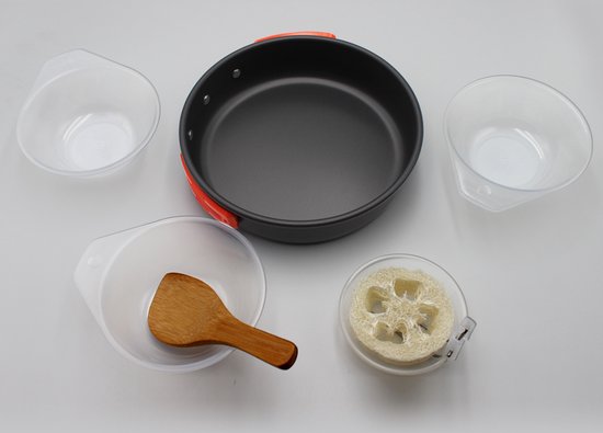 Zwarte camping kookpan met oranje handvat, mokken, spatel en loofah.