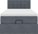 Donkergrijs bed met gestoffeerd hoofdbord, witte matrastopper en geïntegreerde opbergruimte.