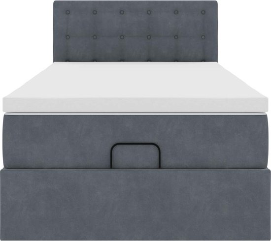 Donkergrijs bed met gestoffeerd hoofdbord, witte matrastopper en geïntegreerde opbergruimte.