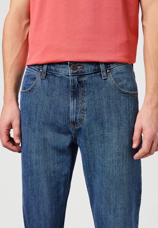 Dichtbij de voorkant van een blauwe spijkerbroek, met knoopsluiting en zakken.