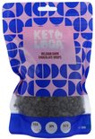 Een lichtroze pak met een blauw patroon. De tekst 'KETO & LOGA BELGIAN DARK CHOCOLATE DROPS' is zichtbaar. Chocoladedruppels zijn zichtbaar onderaan.