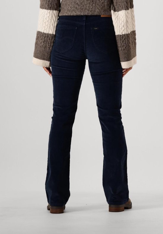 Achterkant van een model in donkerblauwe corduroy jeans met flared pijpen.