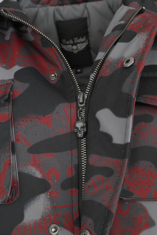 Sluiting van een jas met camouflageprint in grijs, zwart en rood, met een doodskop als ritsdetail.