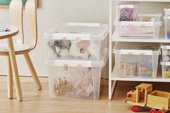 Twee transparante opbergboxen op de vloer, gevuld met speelgoed en knuffels, naast een kinderstoel.