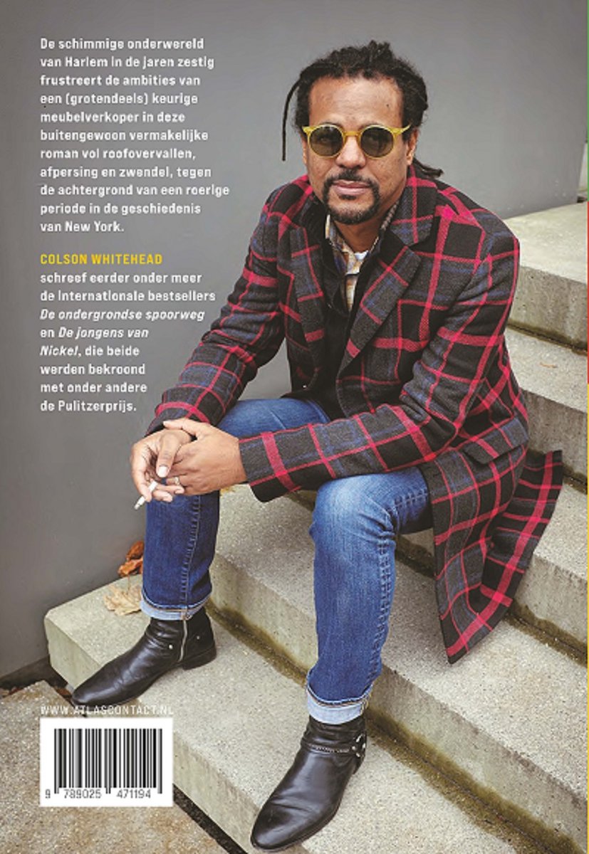 Colson Whitehead zit op trappen, een sigaret in zijn hand, gekleed in een geruite jas en spijkerbroek.