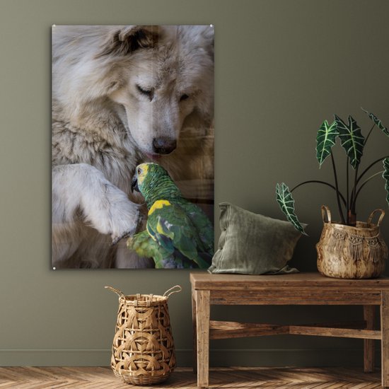 Een witte hond en een groene papegaai op een glasafbeelding boven een houten bankje.