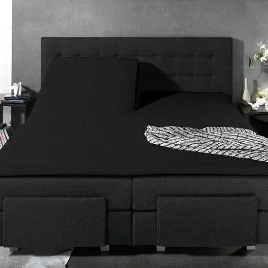 Een groot zwart bed met een opengeslagen hoeslaken en een deken.