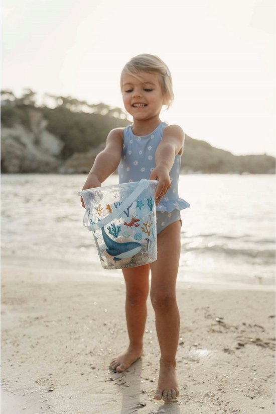 Meisje op het strand met een lichtblauwe emmer met zeelevenprint.