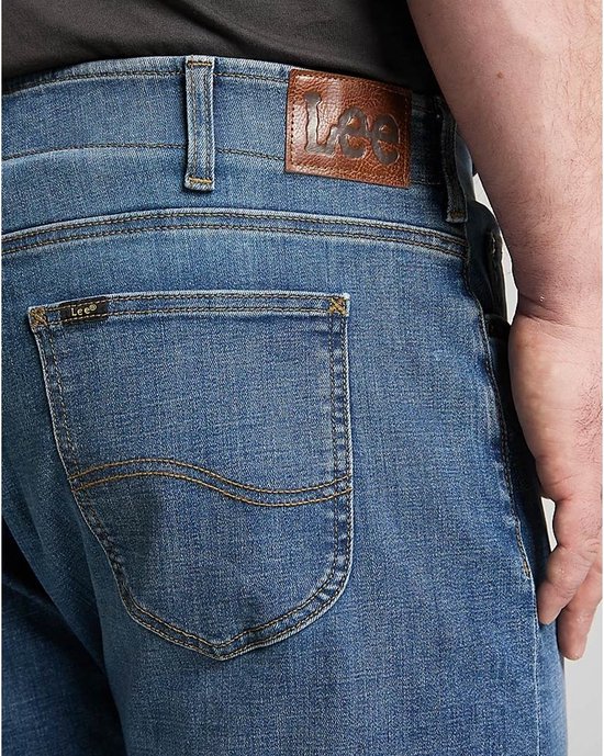 Close-up van de achterkant van een lichtblauwe jeans met het Lee-logo op de leren patch en op een klein label.