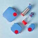 Blauwe lunchboxen en zilveren drinkflessen met rode en blauwe accenten op een blauwe achtergrond.