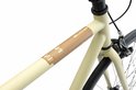 Detail van het middenframe van de crèmekleurige damesfiets met logo.