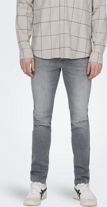 Man in grijze spijkerbroek en beige geruit overhemd.