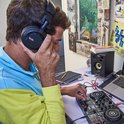 Man met een blauw-gele hoodie, luisterend naar een DJ-set met zwarte koptelefoon.