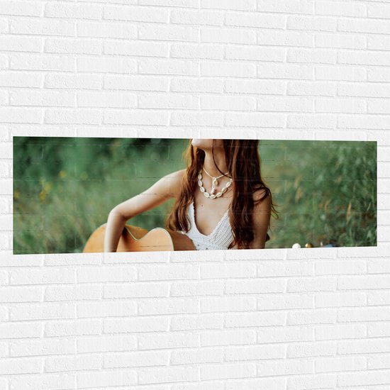 Muursticker - Hippie Vrouw Spelend op Houten Gitaar in Grasveld - 150x50 cm Foto op Muursticker