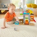 Kind speelt met de Fisher-Price bouwplaats-speelset en een grijze steen op een wit tapijt.