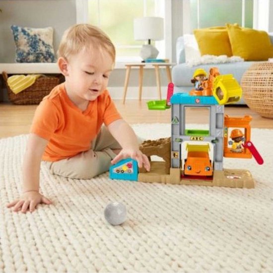 Kind speelt met de Fisher-Price bouwplaats-speelset en een grijze steen op een wit tapijt.