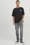 Man met donkere grafische t-shirt en grijze jeans.
