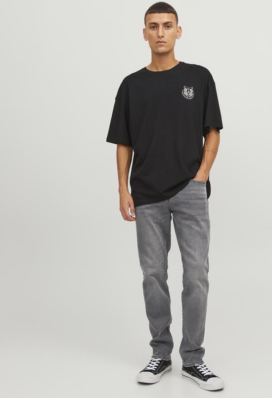 Man met donkere grafische t-shirt en grijze jeans.