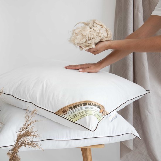 Twee witte kapok kussens, met een stapel kapokvezels.