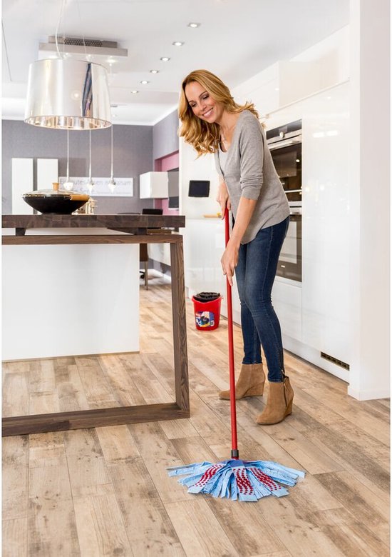 Vrouw met jeans en grijze trui die een blauwe Vileda SuperMocio 3Action mop met rode stippen gebruikt in een keuken.
