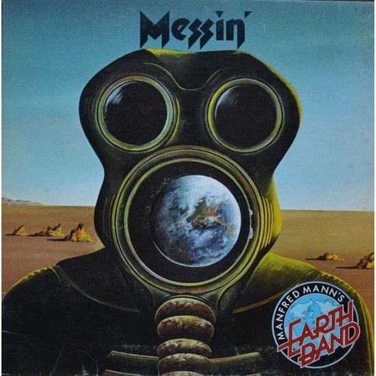 Een groen gasmasker met een afbeelding van de aarde in de lens. Tekst 'Messin' en 'Manfred Mann's Earth Band'. Woestijnlandschap op achtergrond.