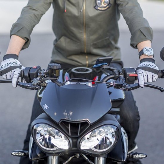 Motorrijder met zwarte handschoenen en Quad Lock stuurbevestiging op een motor.