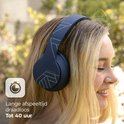 Vrouw met blonde haren draagt een donkerblauwe PowerLocus koptelefoon met geometrisch patroon. Lange afspeeltijd, tot 40 uur.