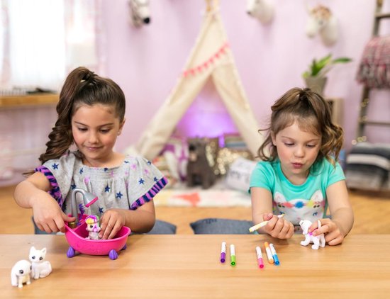 Twee meisjes kleuren op een houten tafel met Crayola Washimals. Een meisje kleurt een roze badje.