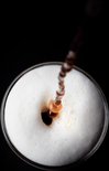 Bovenaanzicht van koffie die in een glas met schuim wordt geschonken.
