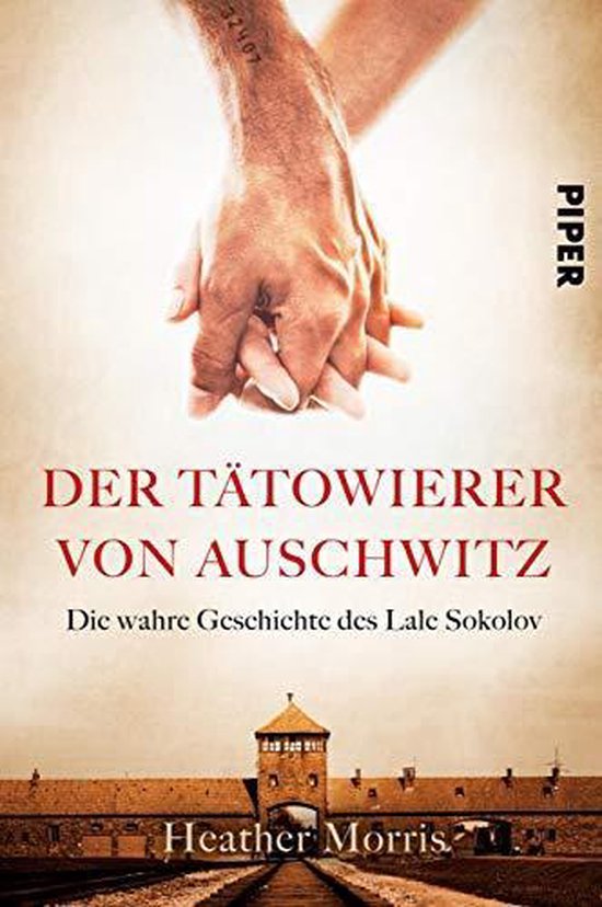 Boekomslag van 'De Tatoeëerder van Auschwitz' met gekoppelde handen met tatoeagenummer en poort van Auschwitz.