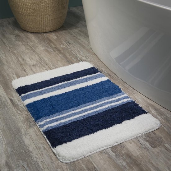 Tapis de bain à rayures bleues, blanches et bleu marine à côté d'une baignoire.